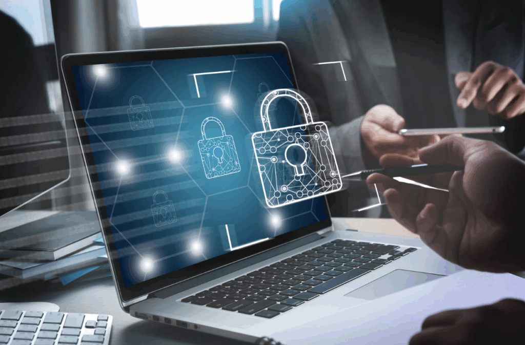 Hacker in hoodie reaching through laptop with open padlock graphic on screen.