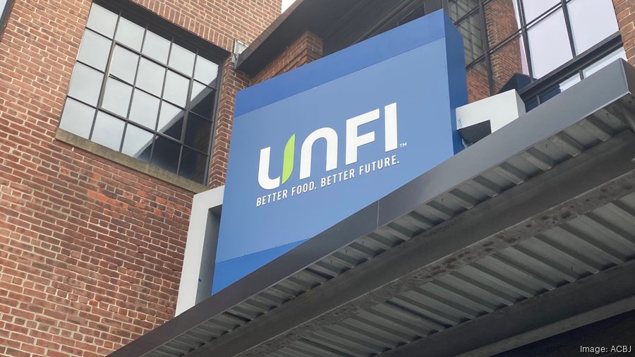 Sign for UNFI (United Natural Foods, Inc.) with the slogan “Better Food. Better Future.” displayed on the exterior of a brick building.